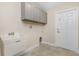 Bright laundry room with utility sink, cabinets, and door to exterior at 7398 Petal Rd, North Port, FL 34291