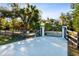 Ornate black gate opens to a long driveway, with lush landscaping and wooden fencing at 17221 Elder Ave, Port Charlotte, FL 33954
