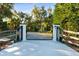 Ornate black metal gate with white pillars and wood fencing at 17221 Elder Ave, Port Charlotte, FL 33954
