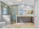 Modern bathroom with a glass-enclosed shower, dual sinks, and gray cabinetry at 17466 Fuego Ln, Punta Gorda, FL 33955