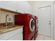 Laundry room area features a utility sink, granite countertop and modern red washer and dryer at 3948 La Costa Island Ct, Punta Gorda, FL 33950