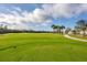 Green golf course with palm trees and a partly cloudy sky at 14672 Sycamore Ct # 3622, Punta Gorda, FL 33955