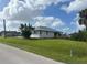 Side view of a house with a wooden porch, green grass, and a street view at 200 Dolphin Pkwy, Punta Gorda, FL 33950