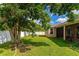 Large backyard with lush grass, mature trees, and a screened patio at 2507 Hobblebrush Dr, North Port, FL 34289