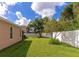 Backyard with green grass, a large tree, and a white fence at 2507 Hobblebrush Dr, North Port, FL 34289