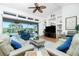 Living area with ample seating, wood flooring, ceiling fan, built-in shelves, and a large TV at 3700 Candia Dr, Punta Gorda, FL 33950