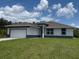 Charming single-story home boasts a two-car garage, neutral paint, and well-manicured lawn against a blue sky at 384 Prineville St, Port Charlotte, FL 33954