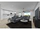 Modern open-concept living room and kitchen with white cabinets, a large sectional sofa, and wood-look tile floors at 384 Prineville St, Port Charlotte, FL 33954