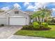 Tan house with two-car garage, landscaping, and palm trees at 5355 White Ibis Dr, North Port, FL 34287