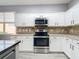 Modern kitchen features white cabinets, stainless steel appliances, neutral countertops, and a stylish backsplash at 1796 Scarlett Ave, North Port, FL 34289