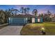 Evening view of a charming blue home with illuminated landscaping and driveway at 18359 Gypsy Ave, Port Charlotte, FL 33954