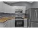 Kitchen with granite countertops, white cabinets, stainless steel appliances, and an electric range at 18359 Gypsy Ave, Port Charlotte, FL 33954