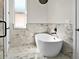 Elegant bathroom featuring a freestanding tub against a marble backdrop and natural light at 4301 Marcella Ter, North Port, FL 34286