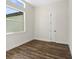 Simple bedroom with wood-look flooring, large window, and white walls at 4301 Marcella Ter, North Port, FL 34286