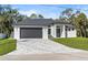 Contemporary home with a long driveway, lush lawn, a modern two-car garage, and impact windows at 4301 Marcella Ter, North Port, FL 34286