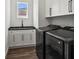 Laundry room with white cabinets, dark countertops, and black washer and dryer at 4301 Marcella Ter, North Port, FL 34286
