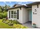 White house with teal door, landscaping, and paved walkway at 14087 Fillmore Ave, Port Charlotte, FL 33981