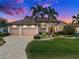 Charming home featuring a three-car garage, lush landscaping, and a well-manicured lawn with palm trees at 1422 Kittiwake Dr, Punta Gorda, FL 33950