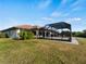 Backyard with screened-in pool, grassy lawn, and water view at 1946 Cove Pointe Dr, Venice, FL 34293