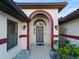Elegant front entry featuring an arched doorway, decorative iron gate, and red accents at 1946 Cove Pointe Dr, Venice, FL 34293