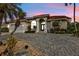 Charming home with a red tile roof, arched entryway, and paved driveway surrounded by tropical plants at dusk at 3730 Whippoorwill Blvd, Punta Gorda, FL 33950