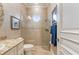 Neutral-toned bathroom featuring tiled walk-in shower with uniquely shaped window, marbled vanity, and attractive decor at 4431 Gardner Dr, Port Charlotte, FL 33952