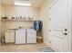 Well-equipped laundry room with ample shelving, modern machines, and a tile floor, adjacent to a paneled door at 4431 Gardner Dr, Port Charlotte, FL 33952
