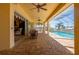 Relaxing covered patio features brick flooring, ceiling fans, wicker furniture, and access to screened pool at 4431 Gardner Dr, Port Charlotte, FL 33952
