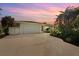 Exterior shot of the home with a spacious driveway, lush landscaping, and a serene sunset backdrop at 210 Divinci Dr, Punta Gorda, FL 33950