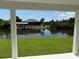 Waterfront view framed by patio posts showing a private dock, serene water, and beautiful landscaping at 9506 Melody Cir, Port Charlotte, FL 33981