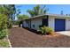 Charming home with a blue garage door, lush landscaping, and manicured mulch beds, showcasing curb appeal at 1108 Ample Ave, Port Charlotte, FL 33948