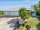 Bright blue house exterior with two car garage and tropical landscaping at 18138 Petoskey Cir, Port Charlotte, FL 33948