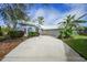 White house with blue accents and a long driveway, surrounded by landscaping at 3116 Silkwood Ln, Port Charlotte, FL 33953