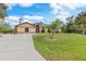 A tan house with a large yard, driveway, and palm trees at 1160 Rizzo St, Port Charlotte, FL 33952