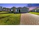 Beautiful single-story home with lush green lawn and a brick driveway leading to a two-car garage at 16031 Alcira Cir, Punta Gorda, FL 33955