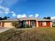 Red house with gray roof, attached garage, and landscaped lawn at 23104 Rountree Ave, Port Charlotte, FL 33980