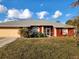 Red house with gray roof, attached garage, and landscaped lawn at 23104 Rountree Ave, Port Charlotte, FL 33980