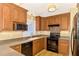 Modern kitchen with wood cabinets, granite countertops, and black appliances at 24 Oakland Hills Ct, Rotonda West, FL 33947