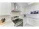 Close-up of the range in a bright kitchen with quartz countertops and a stainless steel range hood at 1425 Park Beach Cir # 149, Punta Gorda, FL 33950