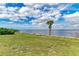 Scenic waterfront view featuring lush green space, a palm tree, and a bench overlooking the tranquil water at 1425 Park Beach Cir # 149, Punta Gorda, FL 33950