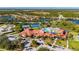 Aerial view showing community clubhouse, pool, tennis courts, and parking at 2427 Daisy Dr, North Port, FL 34289