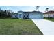 Charming single-story home featuring a well-manicured lawn, gray exterior, and a two-car garage at 5587 E Price Blvd, North Port, FL 34288
