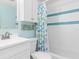 Clean bathroom with white vanity, teal shower, and fish-themed curtain at 817 E 6Th St, Englewood, FL 34223