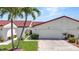 Charming exterior of the home featuring a two-car garage, green lawn and mature palm trees at 1640 Atares Dr # 6, Punta Gorda, FL 33950