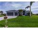 House exterior featuring a two car garage and lush lawn at 180 W Pine Valley Ln, Rotonda West, FL 33947