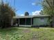 Backyard area with overgrown vegetation and view of the home's screened porch at 14262 Kent Rd, Port Charlotte, FL 33953