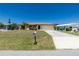 Well-manicured front yard with a spacious lawn, mature landscaping, and a paved driveway leading to an attached garage at 164 Chelsea Nw Ct, Port Charlotte, FL 33952