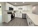 A kitchen showcases stainless steel appliances, white cabinets, black hardware, and gray wood-look flooring at 1100 Belkton Ave, Port Charlotte, FL 33948