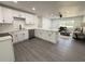 Open concept kitchen features white cabinets, stainless steel appliances, large island, and gray wood-look flooring at 1100 Belkton Ave, Port Charlotte, FL 33948