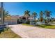 Beautiful home showcasing a well-manicured lawn, palm trees, and an inviting paver driveway, offering curb appeal at 17557 Ohara Dr, Port Charlotte, FL 33948